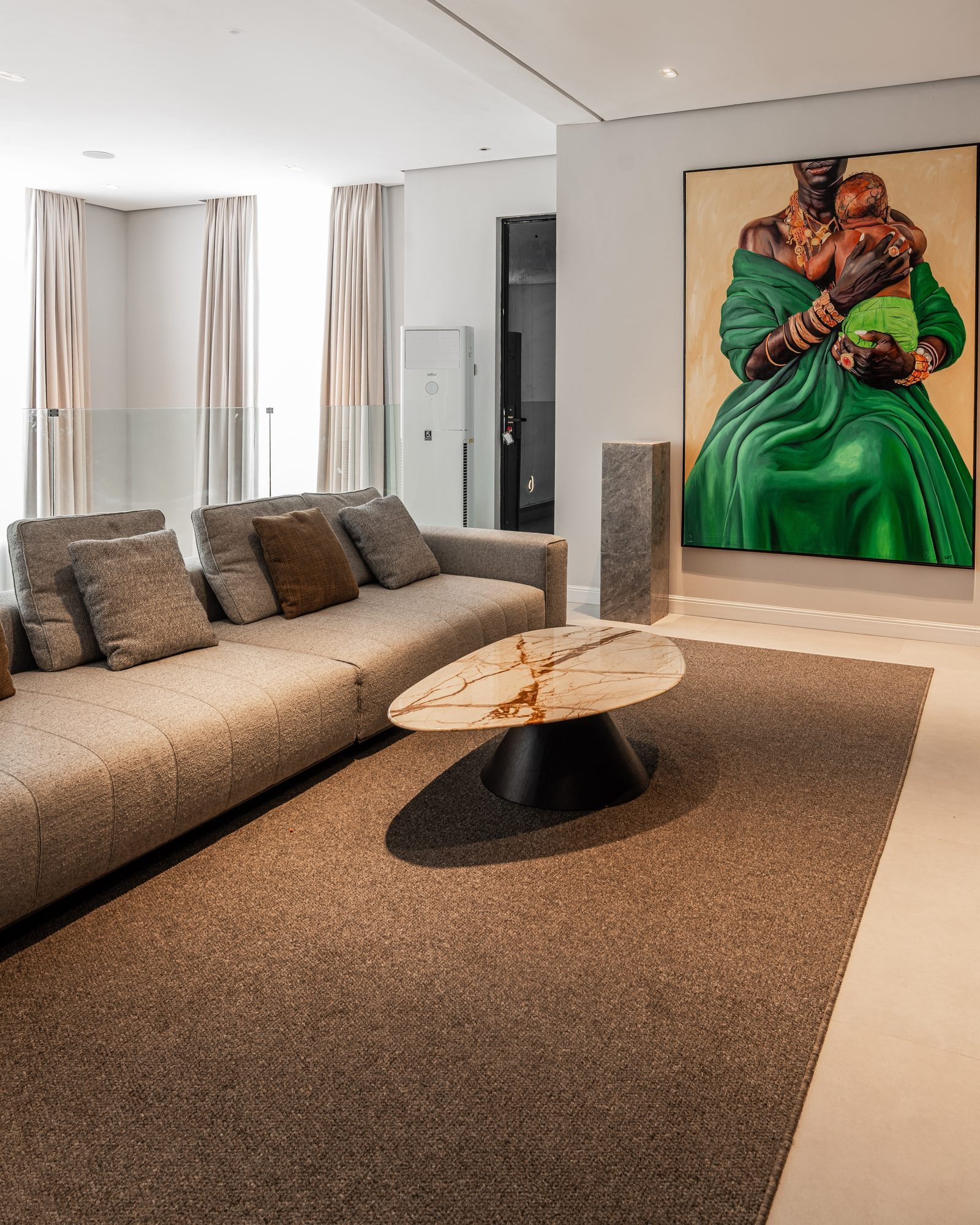 Grey sofa and a saffron-veined marble table before a large green painting