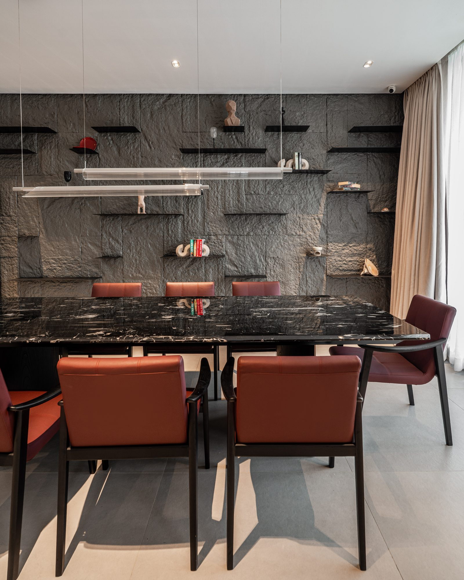 The slate wall up close: floating black shelves holding ceramics, books and a bust
