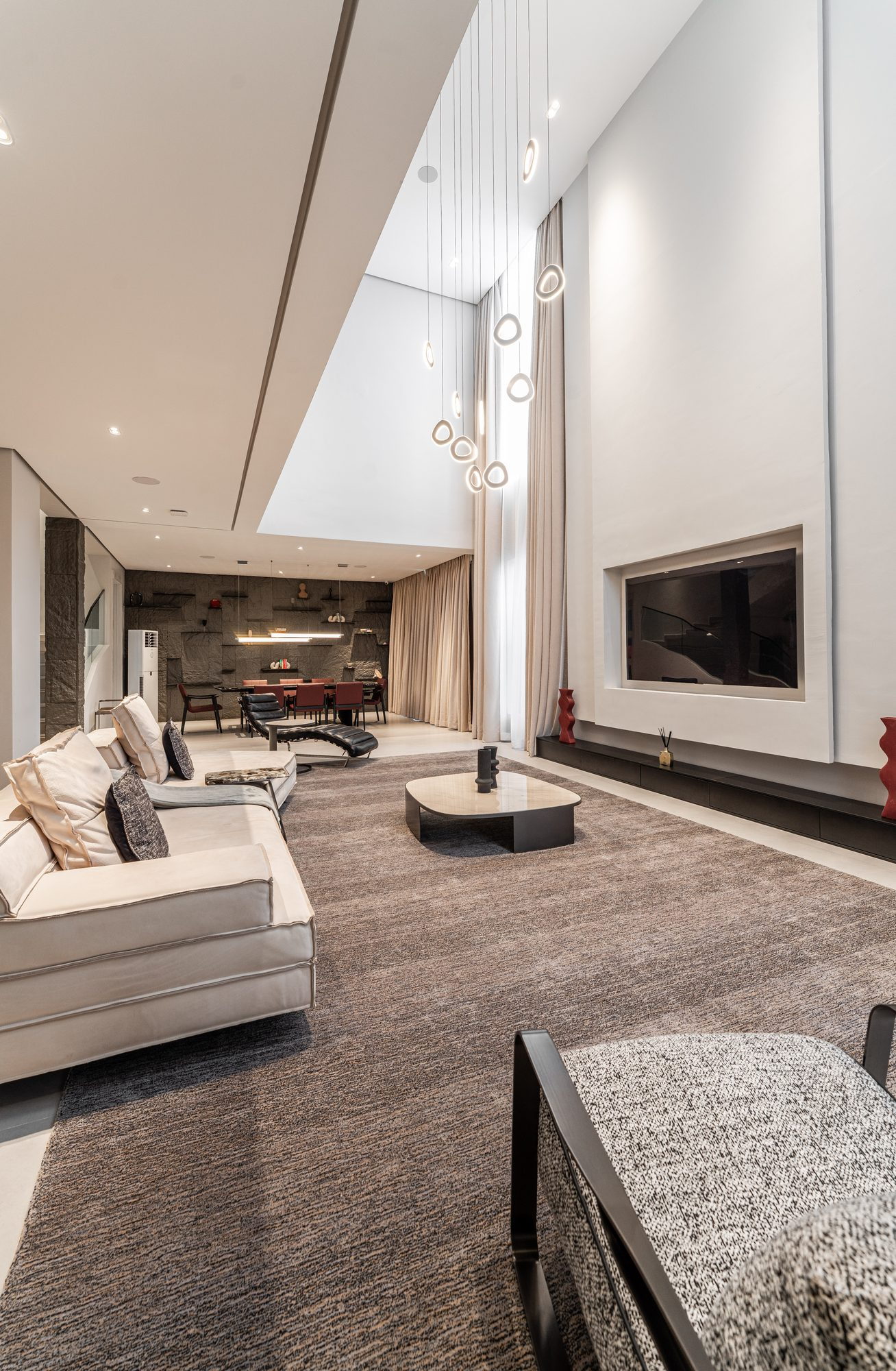The void: floor-to-ceiling curtains, the ring chandelier and the media wall