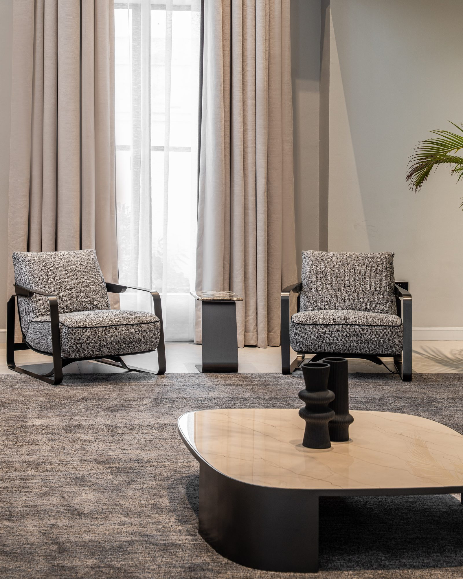 Two bouclé armchairs around a stone coffee table at the window